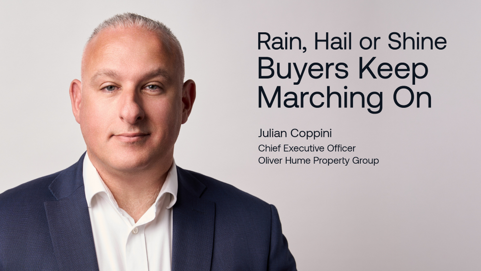 Man in a suit with a neutral expression against a gray background. Text reads: Rain, Hail or Shine Buyers Keep Marching On.